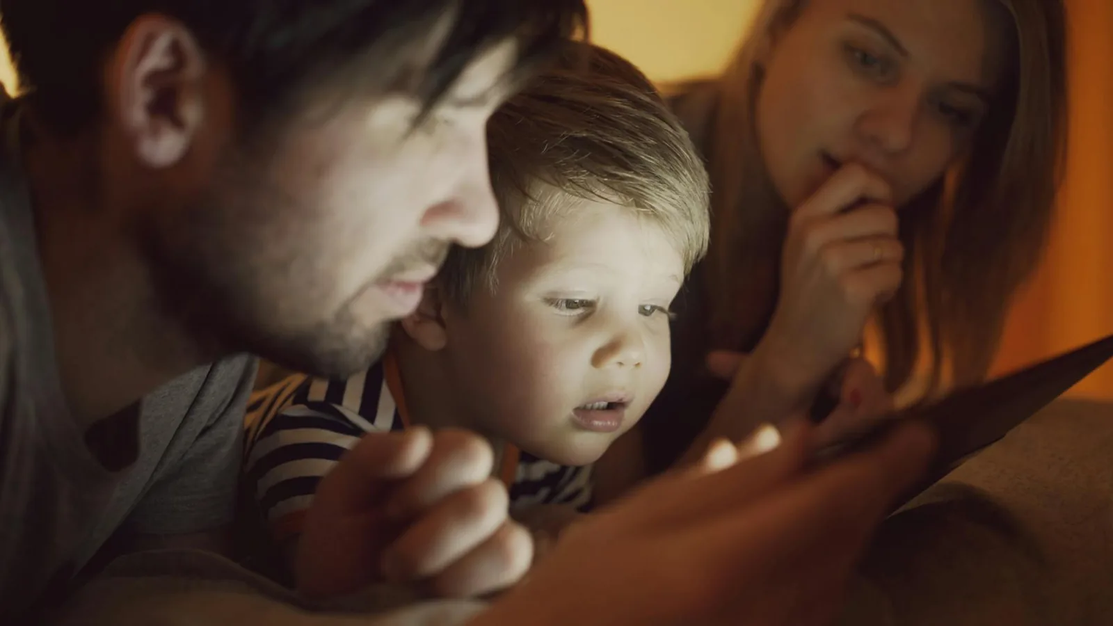 Familie am Tisch mit Smartphone und Uhr als Symbol für Bildschirmzeit und Regeln