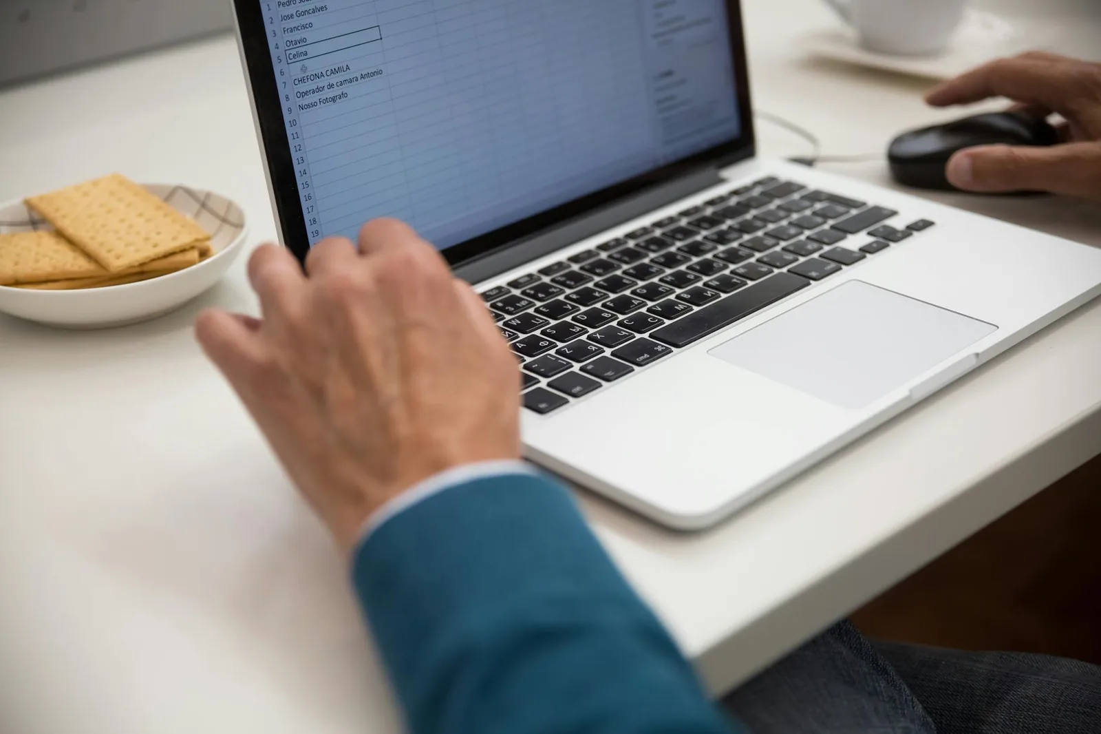 Person arbeitet an einem Laptop mit tabellarischen Daten als Einstieg in Excel-Grundlagen