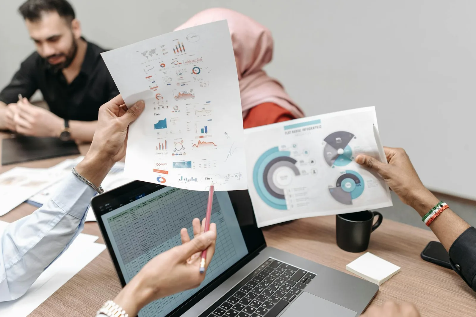 Mehrere Personen arbeiten gemeinsam an einer Tabelle auf dem Laptop