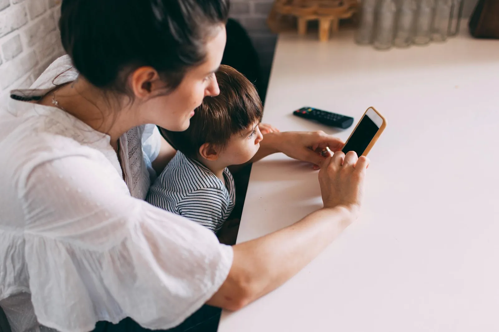 Mutter und Kind richten gemeinsam ein Smartphone ein