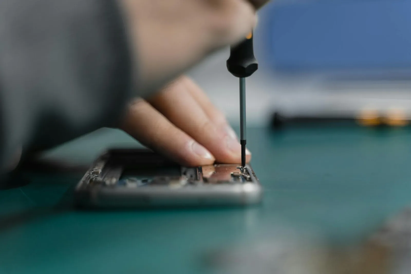 Techniker arbeitet mit Schraubendreher an einem elektronischen Gerät als Symbol für professionelle Handy-Reparatur