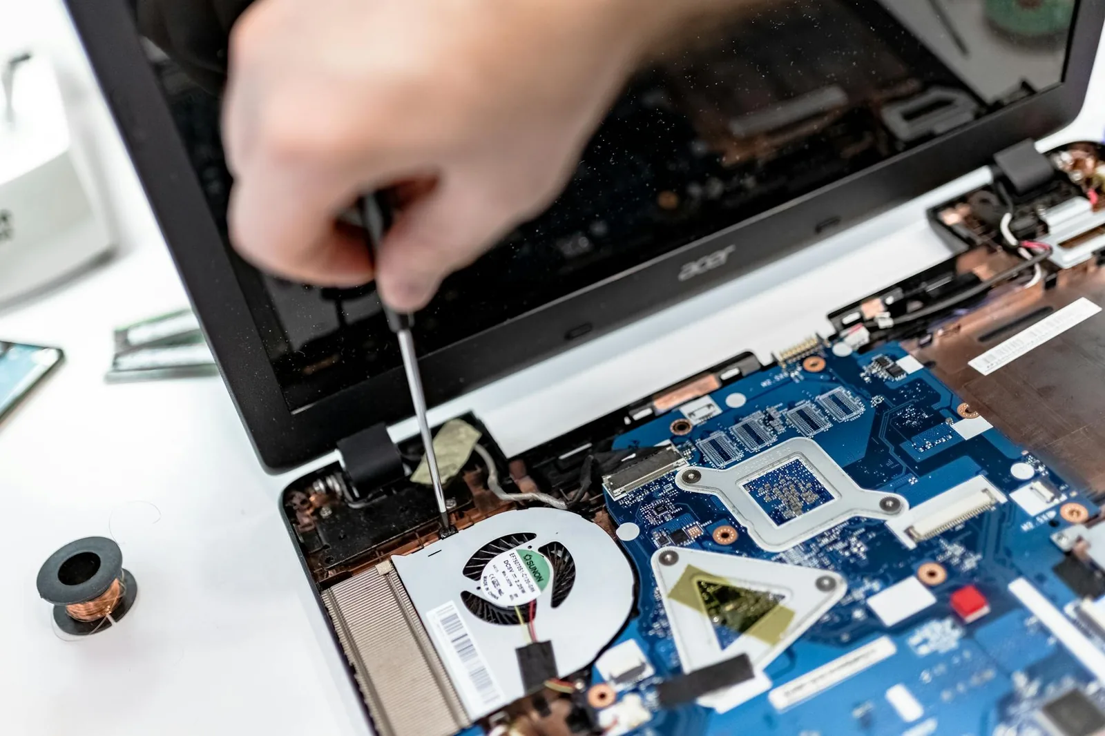 Offener Laptop mit Lüfterbereich und Werkzeug als Symbol für Reinigung und Wartung