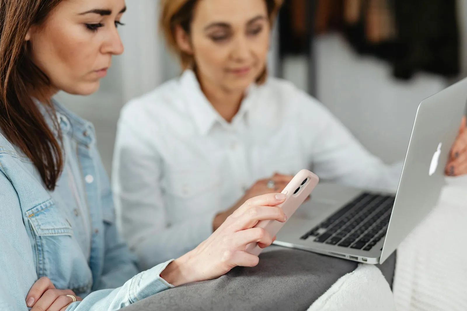 Person nutzt Smartphone am Laptop als Beispiel für Zwei-Faktor-Anmeldung und Passwort-Manager im Alltag