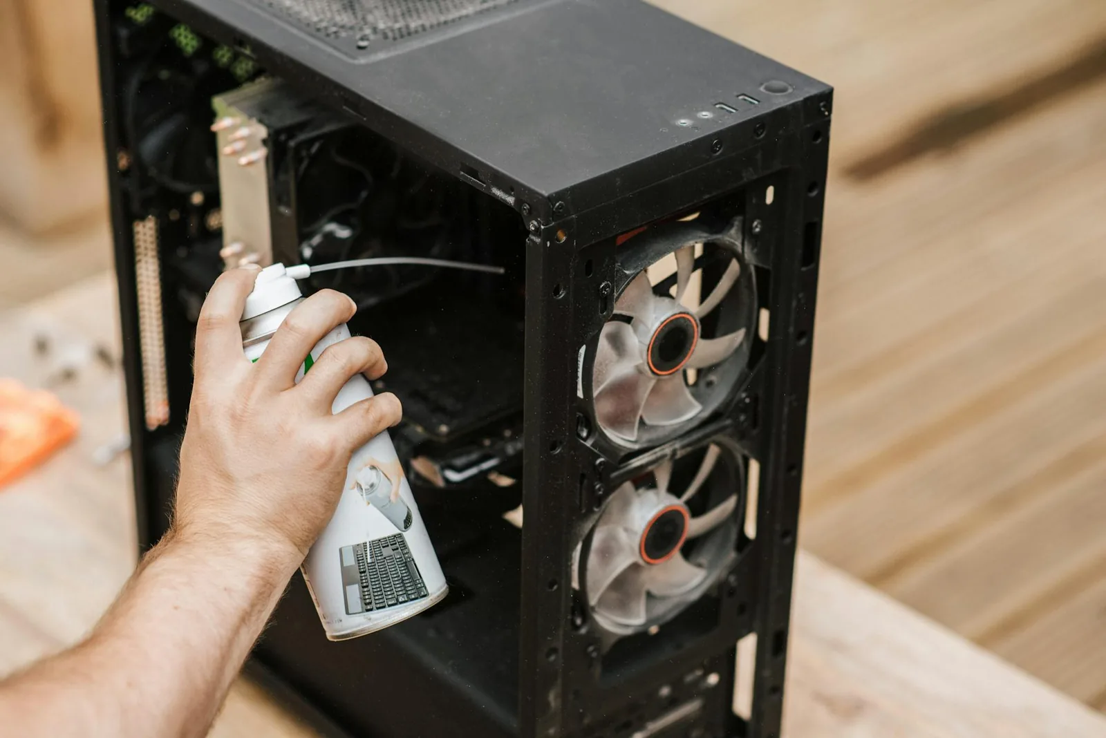 Person reinigt einen geöffneten Computer von Staub als erster Schritt gegen laute PC-Lüfter