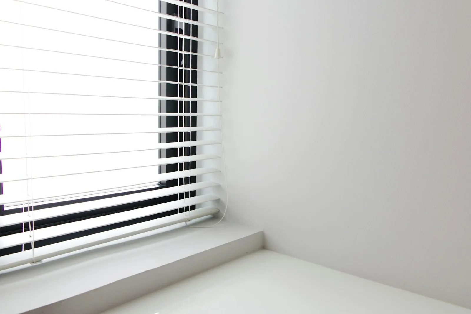Weiße Jalousien am Fenster als Beispiel für Sichtschutz, Lichtsteuerung und automatisierte Beschattung